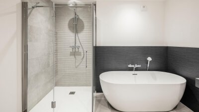 Eckdusche mit einer Tür und zwei Festteilen neben freistehender Badewanne