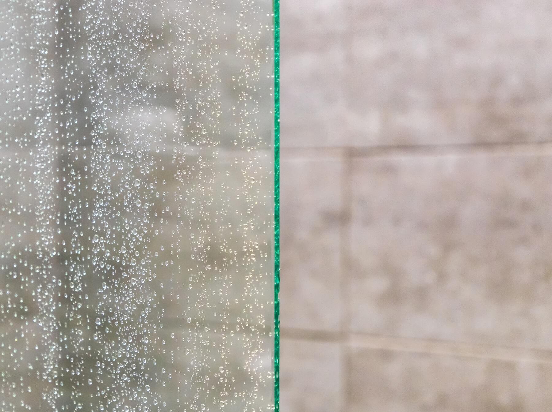 Feine Wassertropfen auf Glasscheibe im Badezimmer