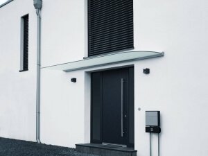 Vordach aus Glas mit Abrundung vor Hauseingang an weißer Fassade