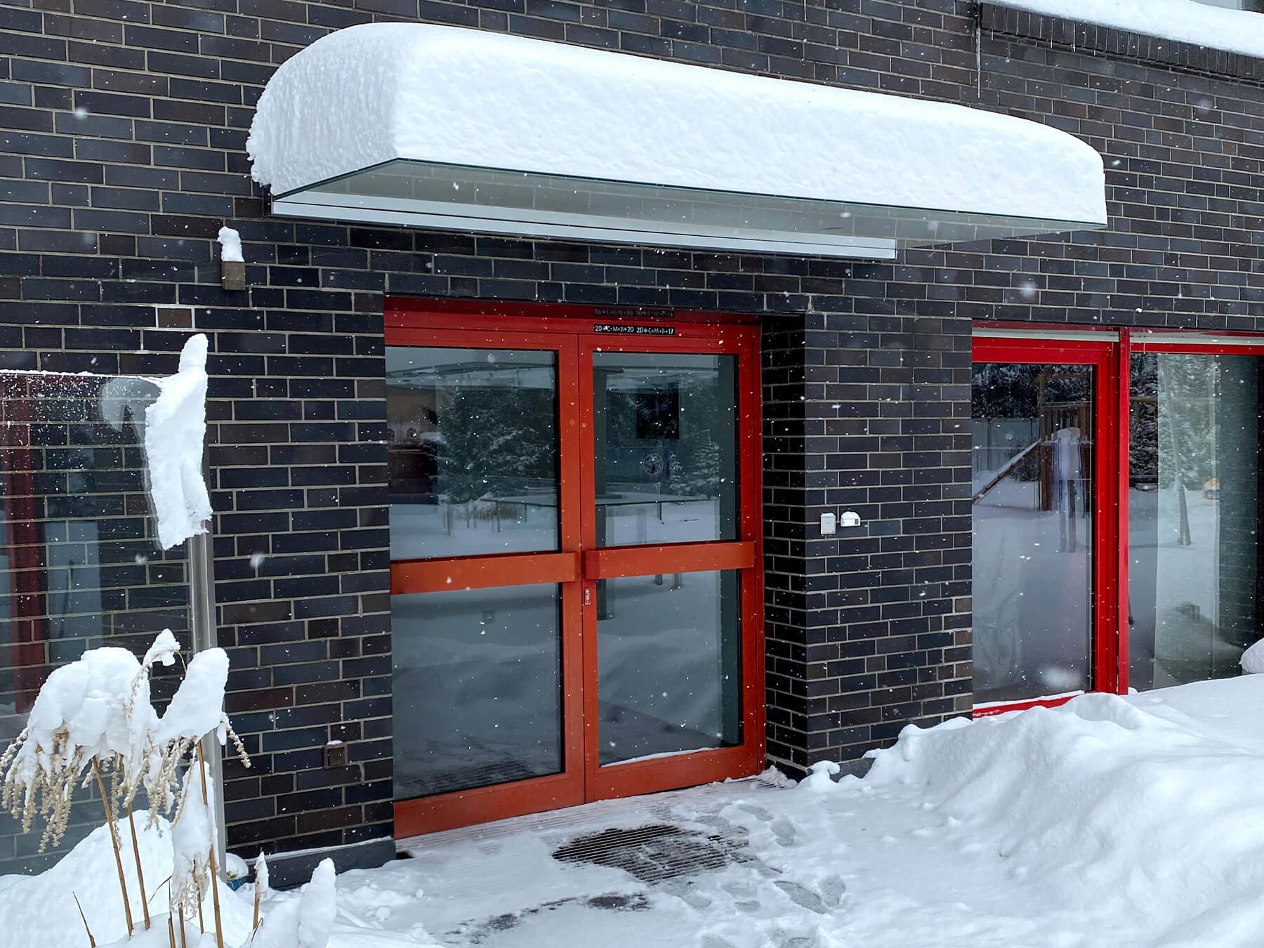 Freitragendes Glasvordach mit Schnee bedeckt vor Hauseingang