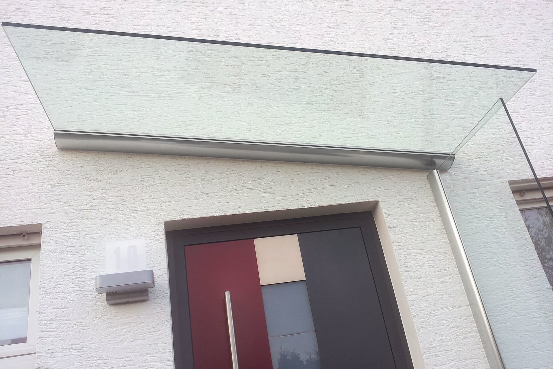 Vordach mit Seitenwindschutz aus Klarglas individuell nach Mass Made in Germany