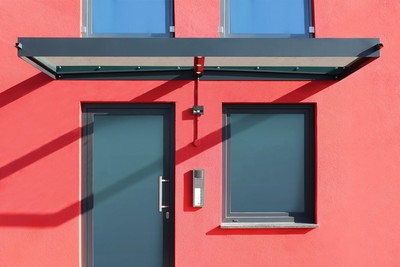 Glasvordach Ella mit zwei Glasscheiben an roter Fassade