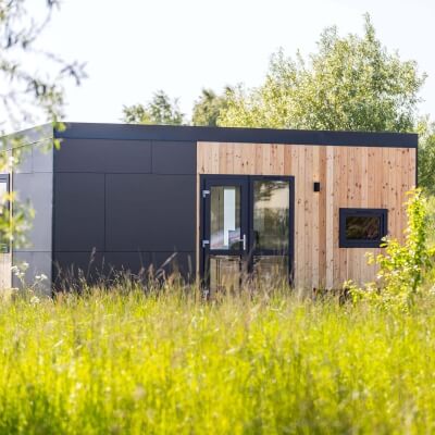 Tiny House mit Holzpaneelen und Pulverbeschichtung im Grünen